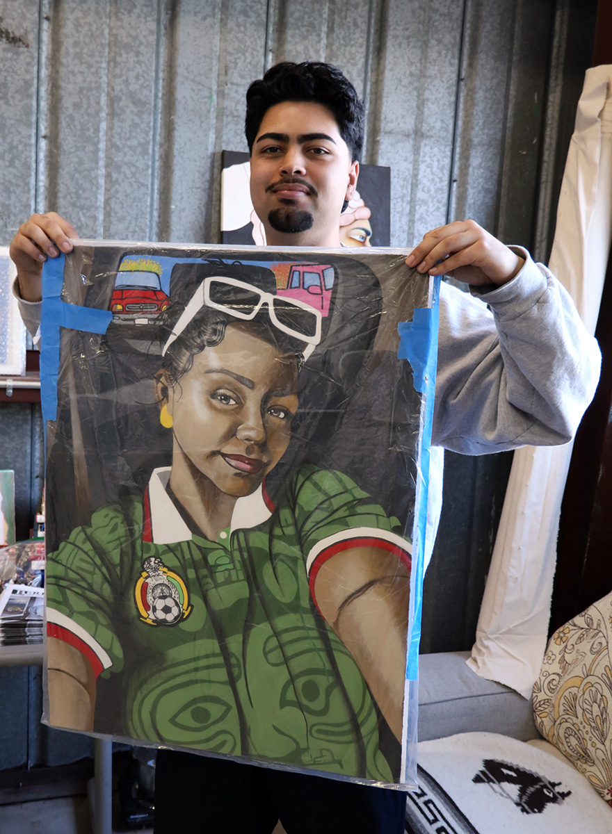 A man holds up a painting wrapped in plastic of a smiling woman