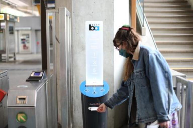 a person takes a printed poem from a dispenser in a BART station