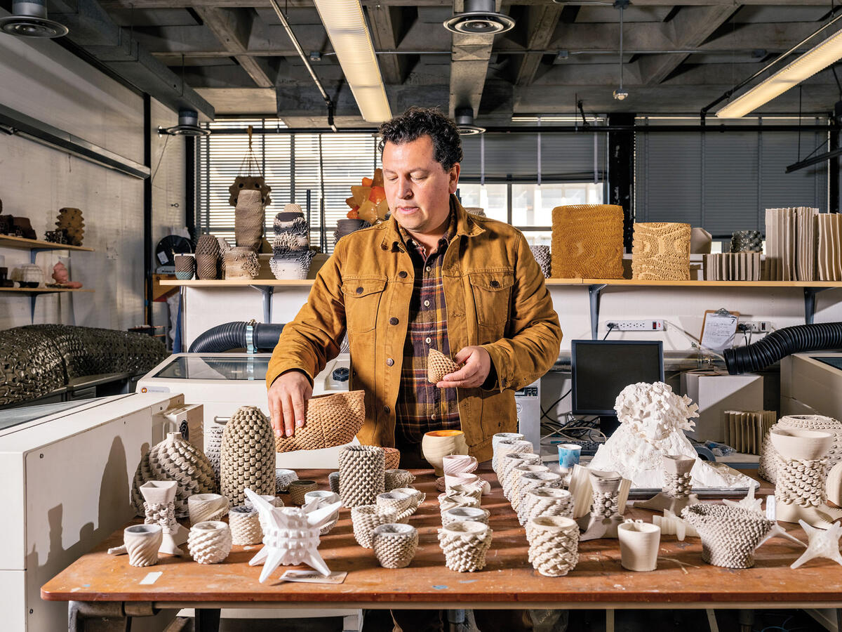 Ronald Rael looking at ceramic pieces 