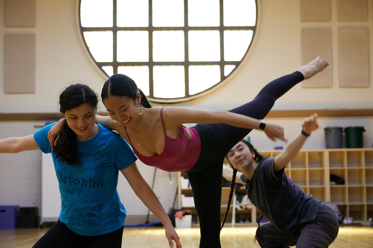 students dance with large round window in background