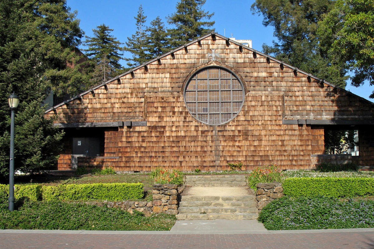 exterior view of brown-shingled building with large round window