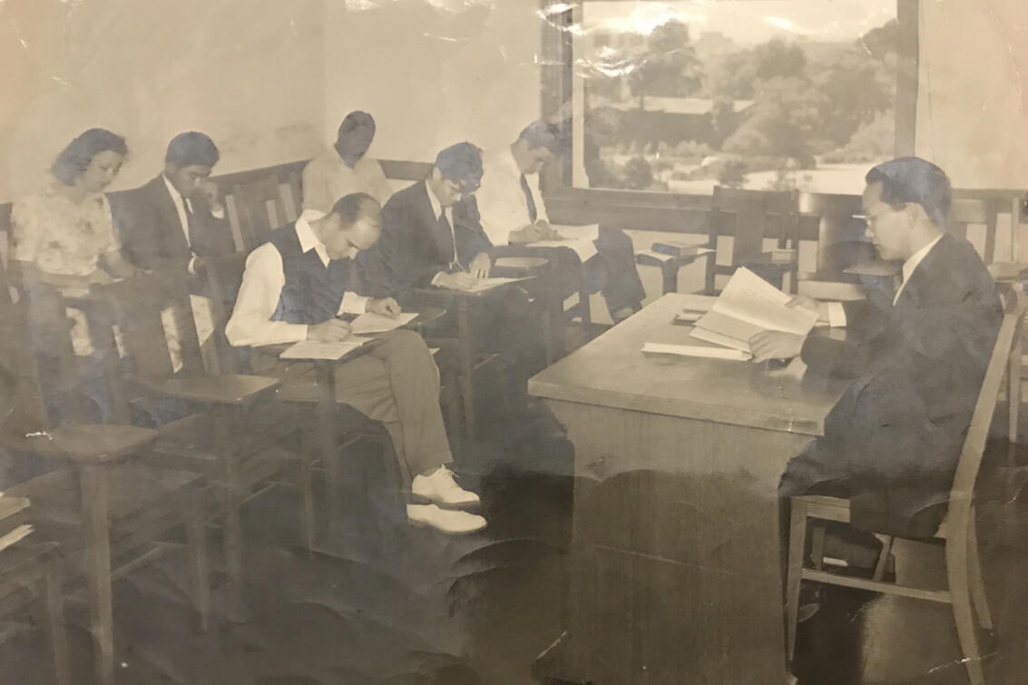 worn black-and-white photo of students with a teacher
