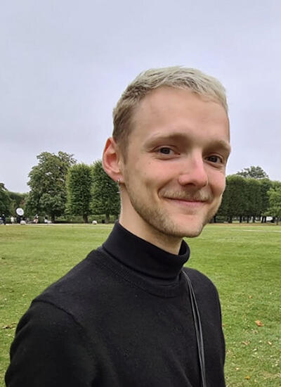 A smiling man stands in a green field