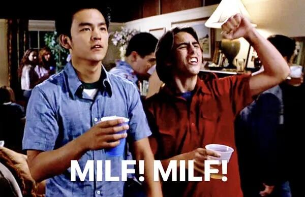 Two individuals standing side by side at a party. Text reads "MILF! MILF!"