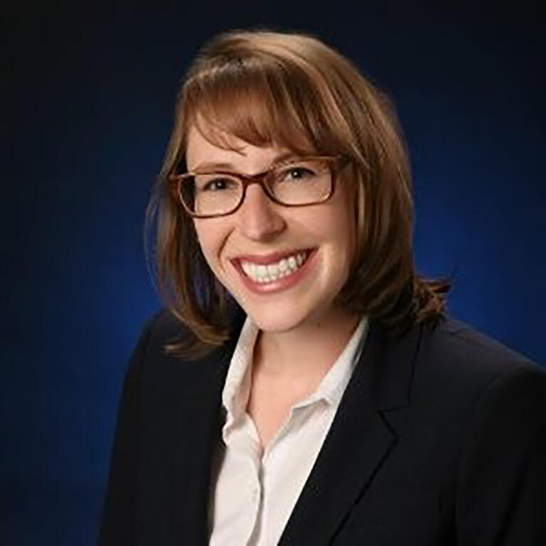 smiling woman with glasses in blouse and blazer