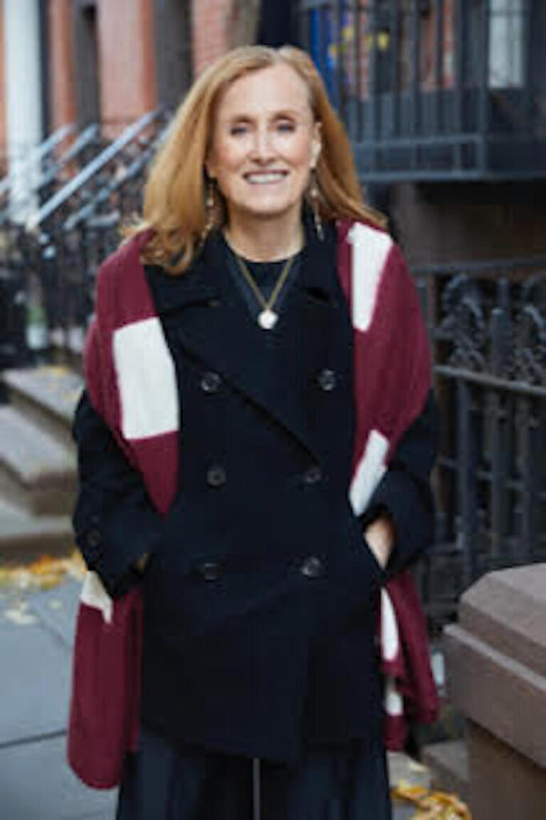 woman in dark jacket and striped scarf smiles at camera