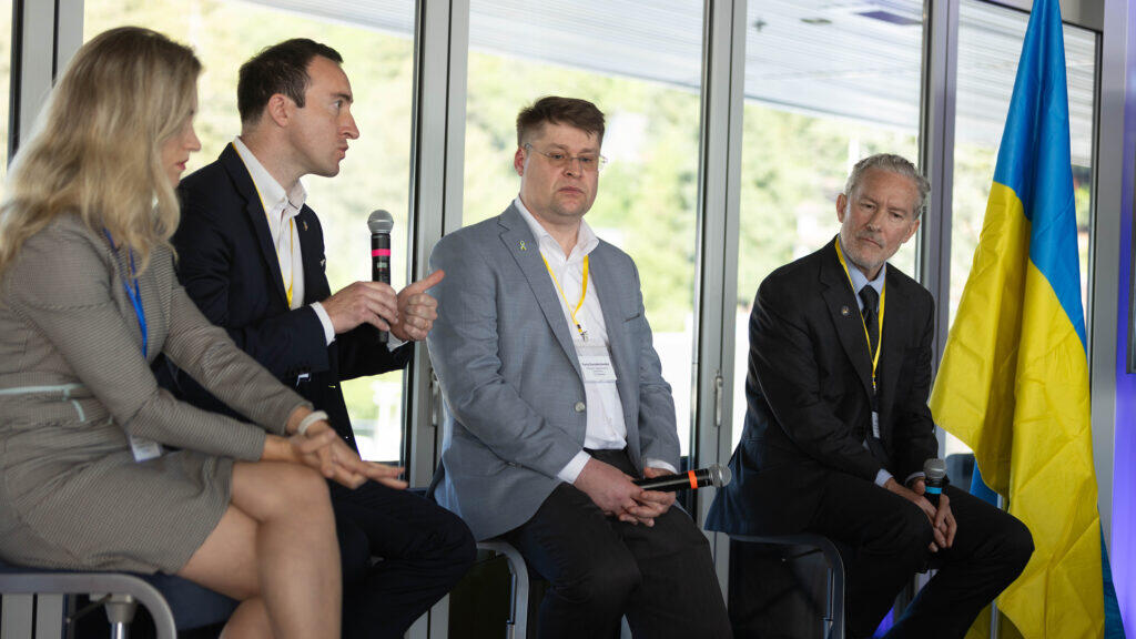 Chancellor Rich Lyons and three others, including Anastassia Fedyk and Yuriy Gorodnichenko, sit next to a Ukrainian flag and discuss the new UC Berkeley-Ukraine innovation Hubs in front of an audience