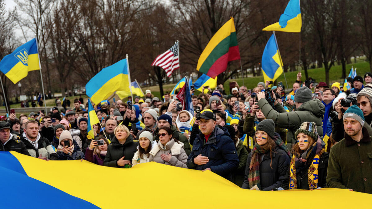 audience members at a rally in support of Ukraine wave Ukrainian flags and the US flag"