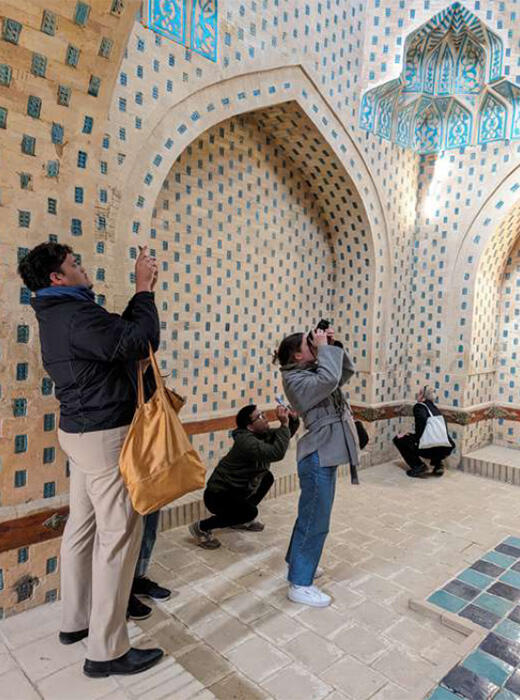 Four people look at and take photos of interior tile design