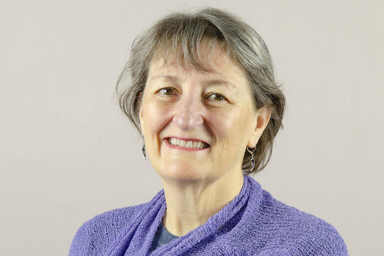 woman in purple top smiles at camera