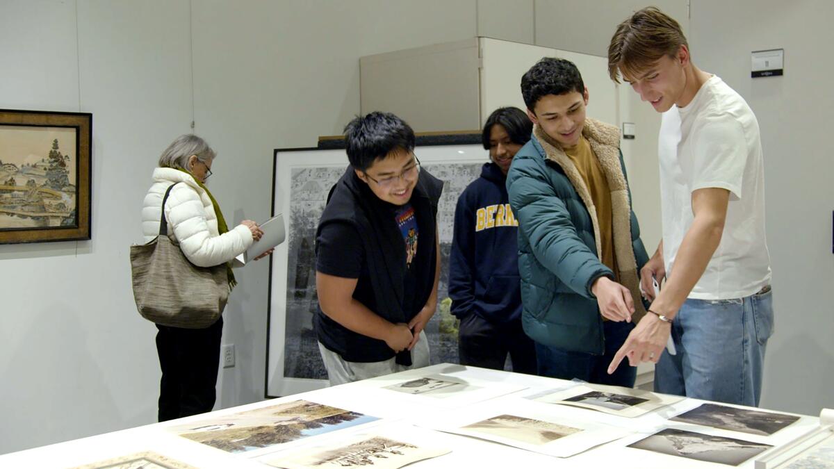 First-year student Virgil Chamblas (right) points to the photos he chose for Five Tables of Art & Climate Change, a one-day pop-up show he helped curate at the campus’s Berkeley Art Museum and Pacific Film Archive (BAMPFA).